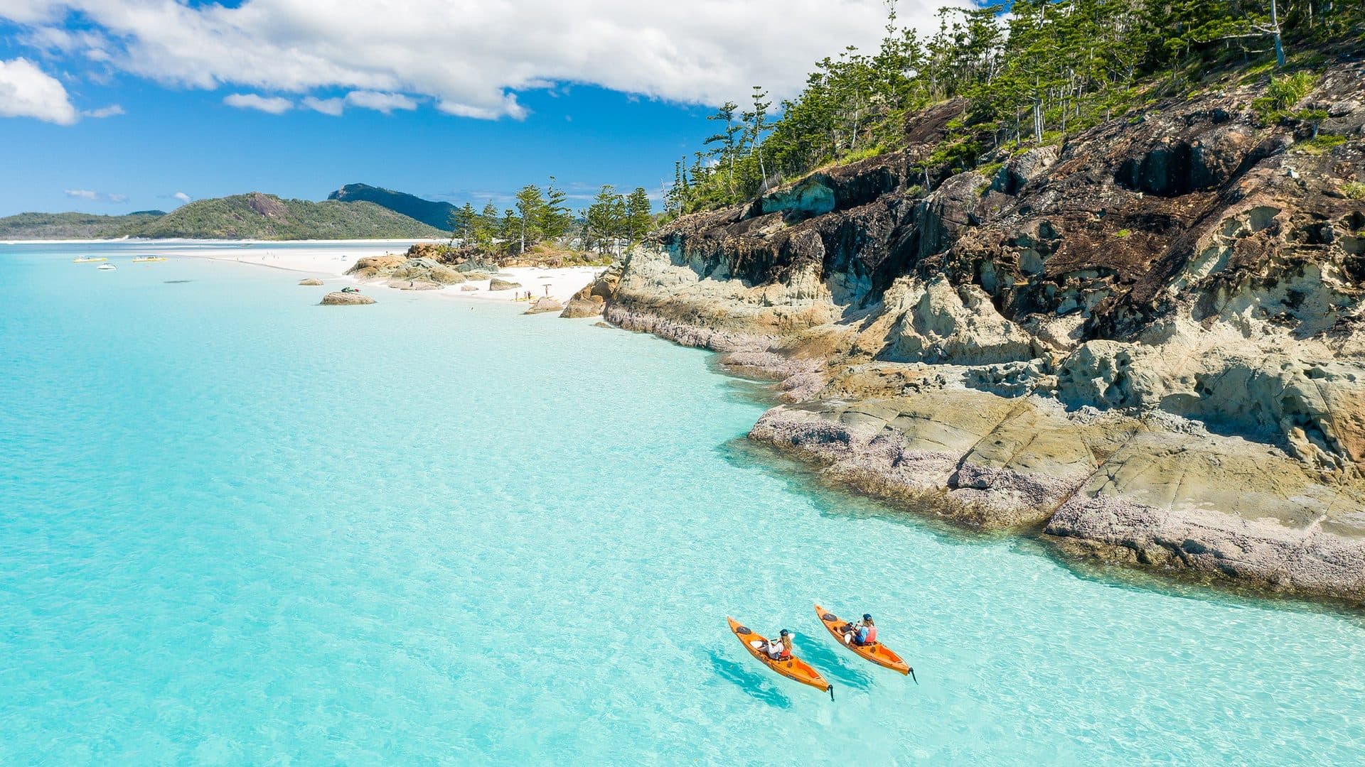 A clear tropical bay with kayaks and a bright blue horizon